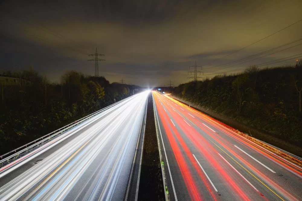 Long exposure shot of a highway at night showing moving red lights in one direction and white lights in the other